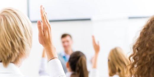 Classroom, 2 women with hands up